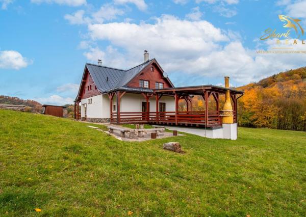 Krásna chata pod lesom s veľkým pozemkom.