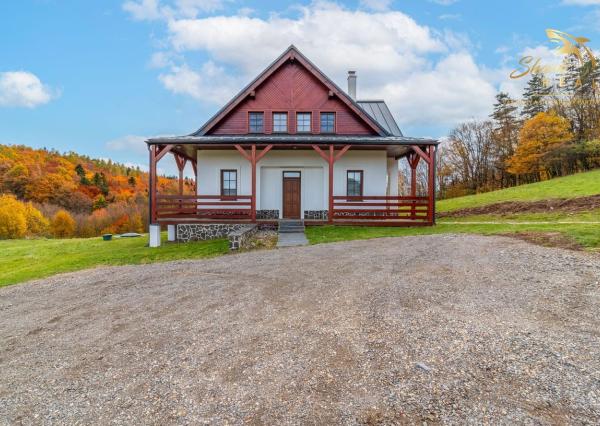 Krásna chata pod lesom s veľkým pozemkom.